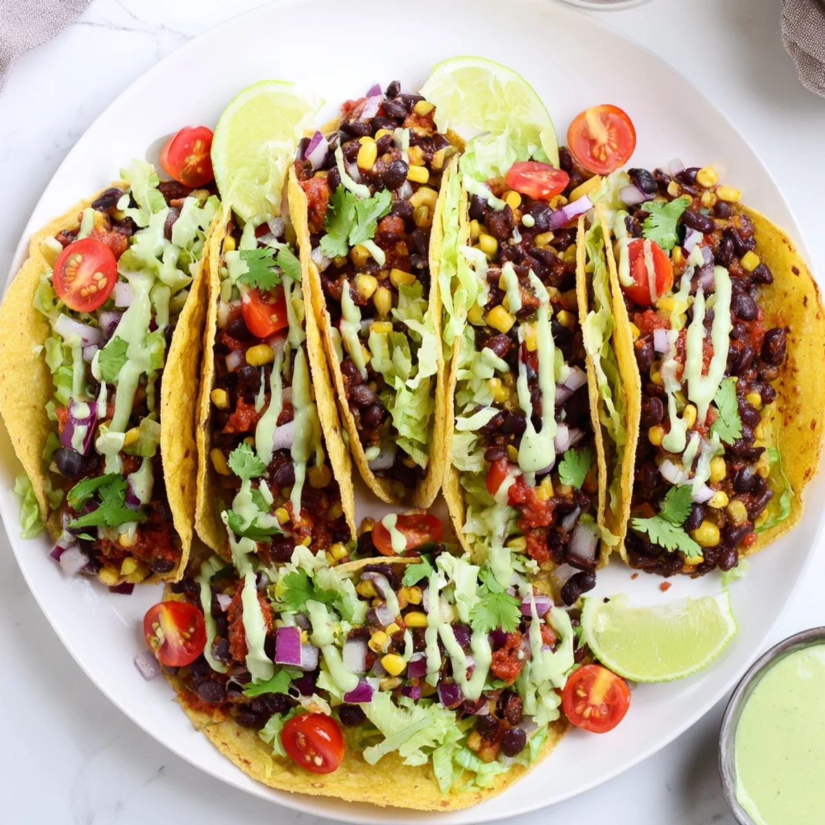 Vibrant Black Bean and Corn Tacos topped with creamy avocado lime crema and fresh cilantro.  
