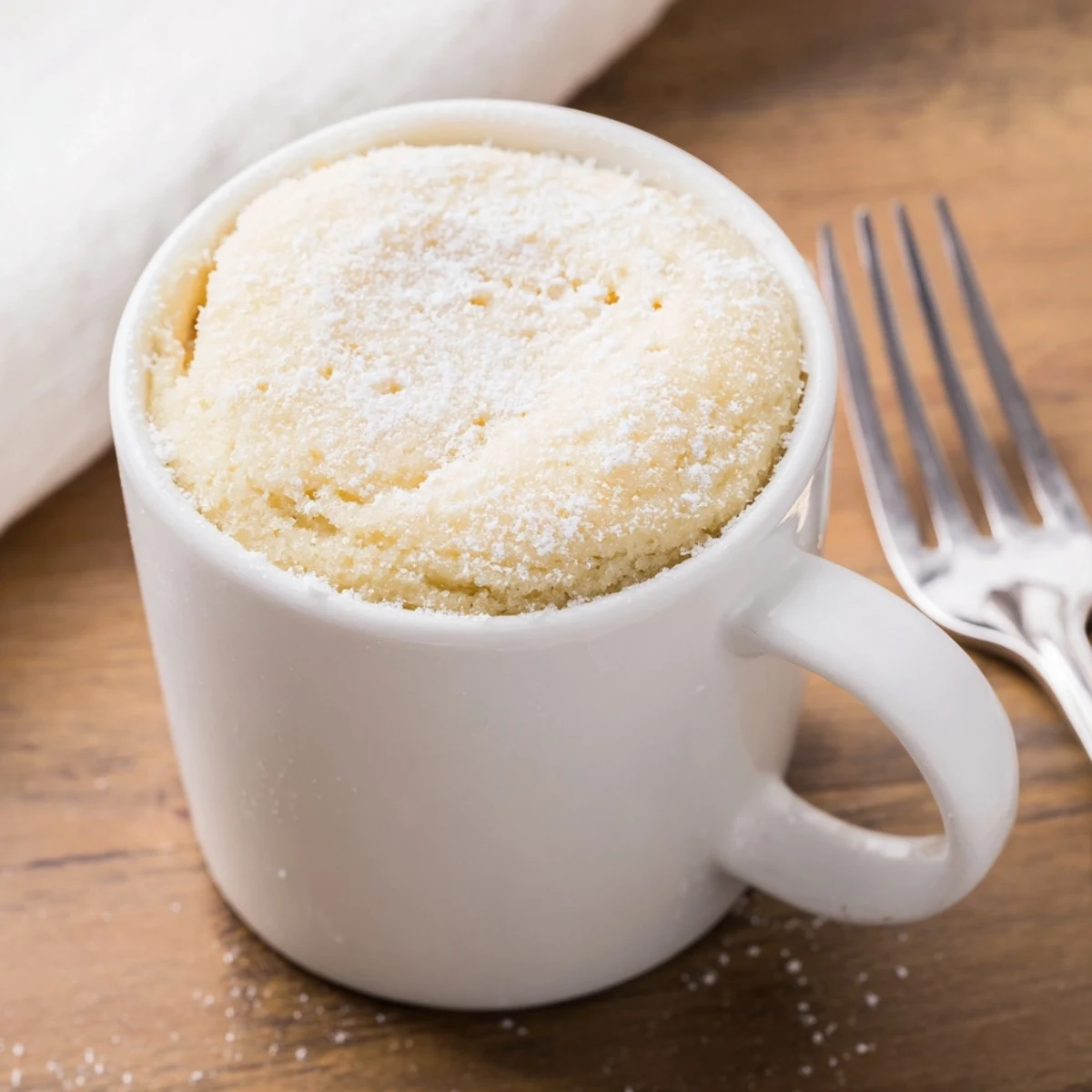 Warm, moist microwave mug cake, a quick dessert topped with a dollop of whipped cream.
