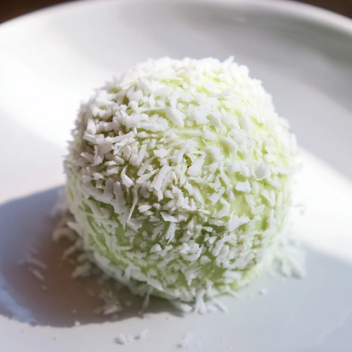 Beautiful round Coconut Matcha Snowball fat bombs, light green with a dusting of coconut.