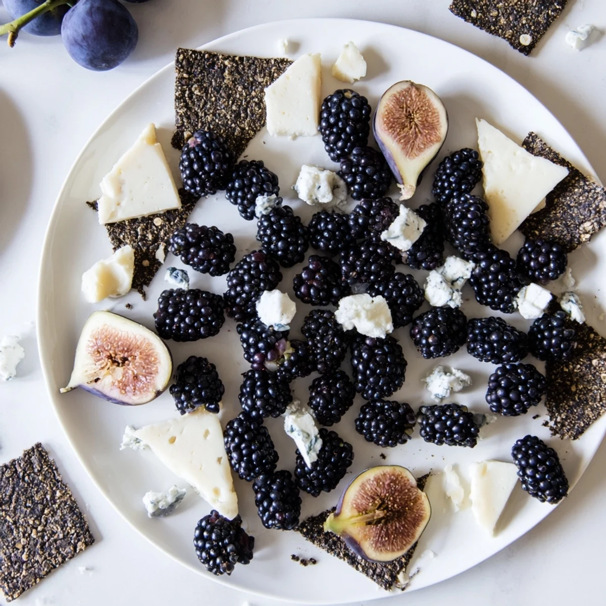 A close-up of a Deep Indigo Midnight Sky cheese board with blackberries and twinkling cheese stars.