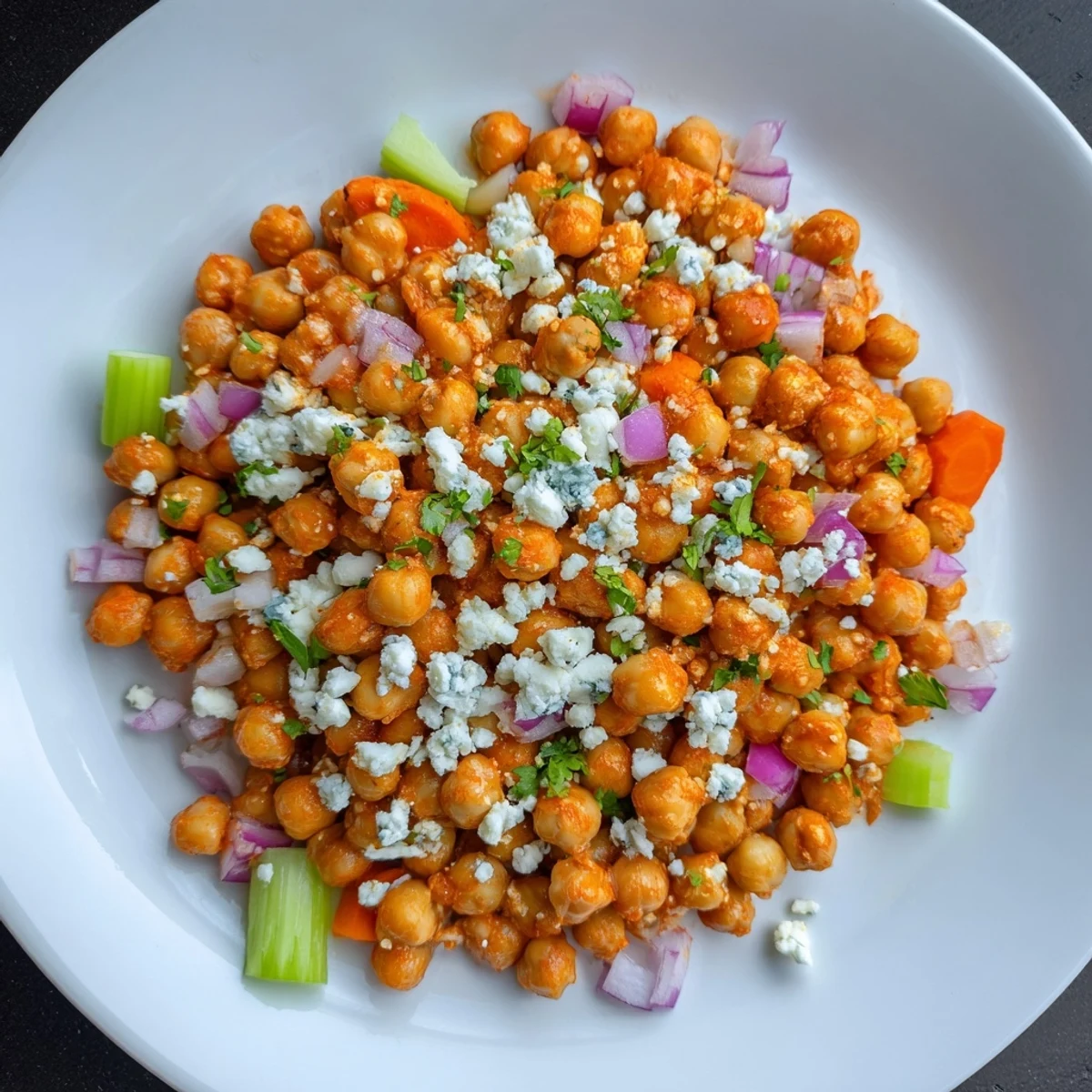 Creamy Buffalo Chicken Bean Salad, tossed with blue cheese and visible, crunchy carrots and celery.