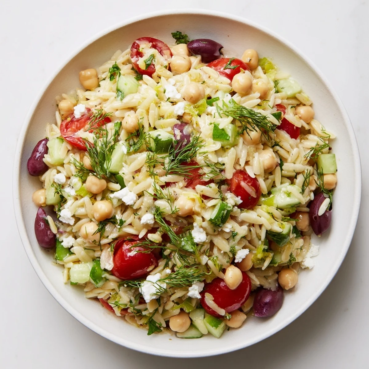 Bright and zesty Greek Lemon-Orzo Bean Salad featuring colorful tomatoes and fresh herbs, ready to serve.
