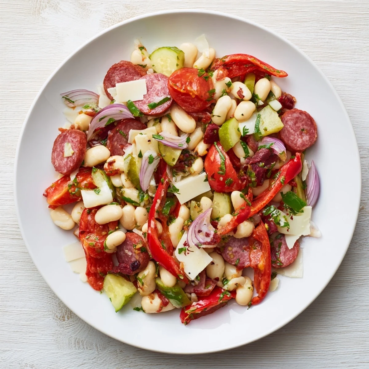 A delicious Italian Antipasto Bean Salad, showing a close-up of salami, provolone, and vibrant tomatoes.