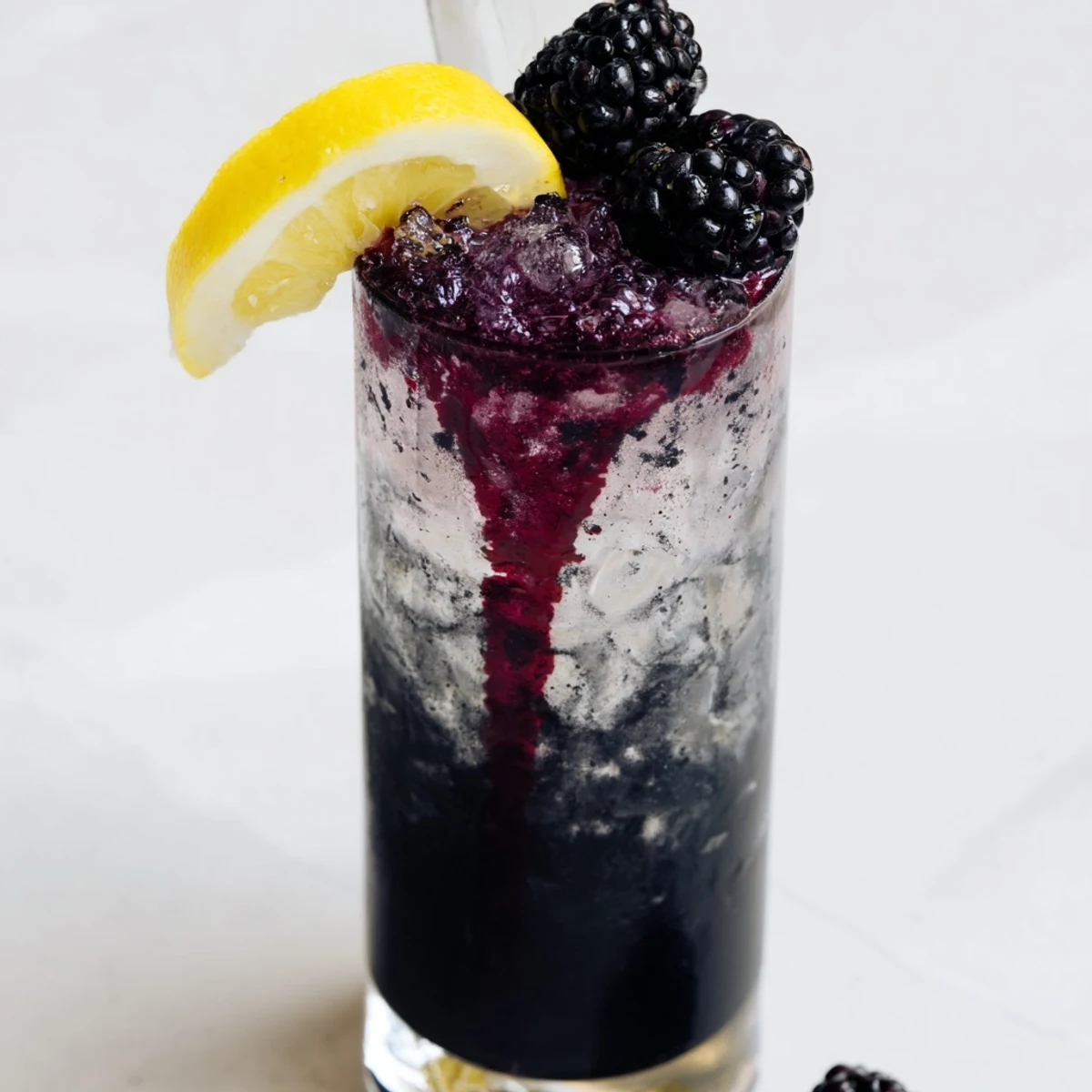 A dramatic Dark Matter Mocktail, layered with inky black charcoal and vibrant blackberry syrup, ready to enjoy.