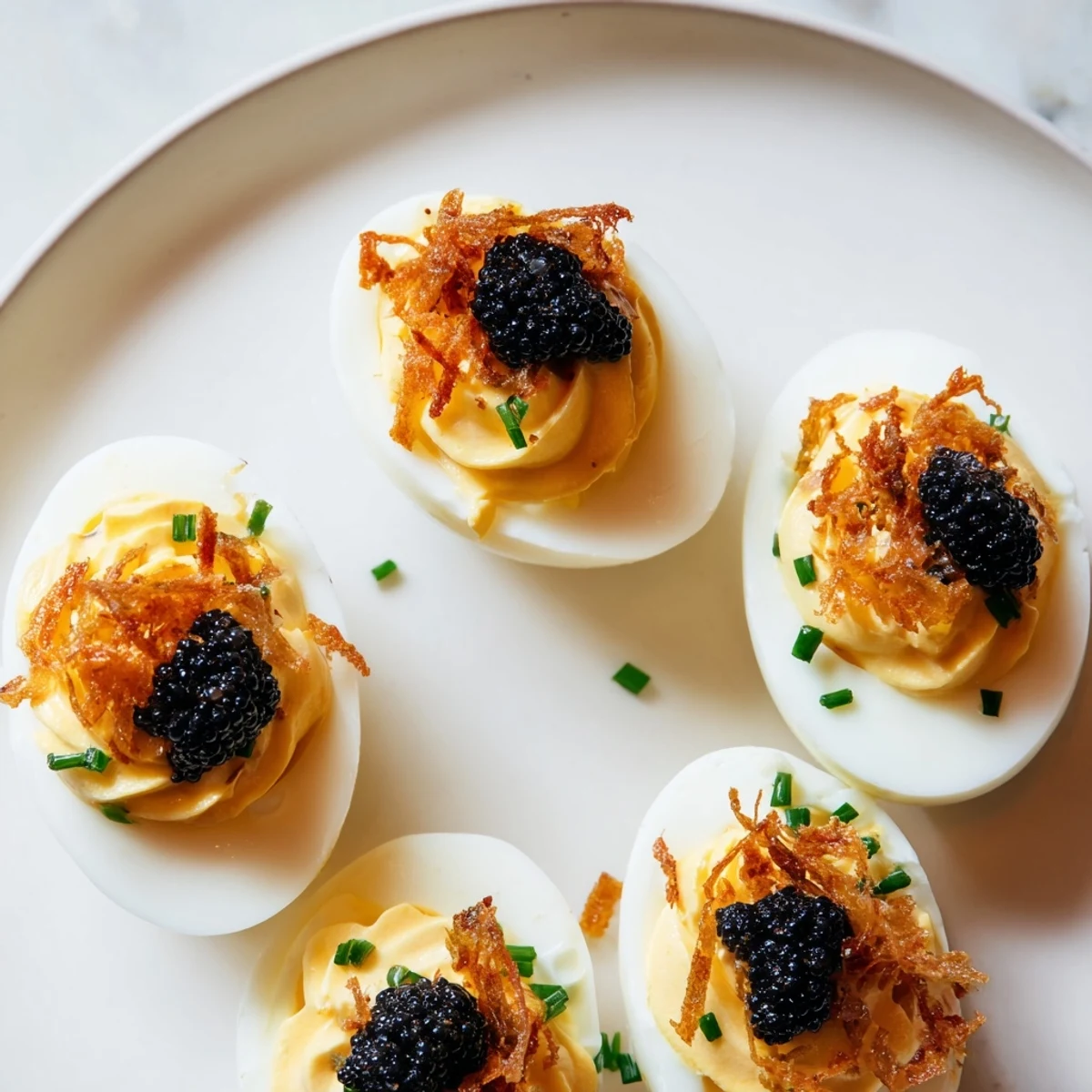 Elegant deviled eggs topped with glistening caviar and a sprinkle of crispy shallots – ready to enjoy.