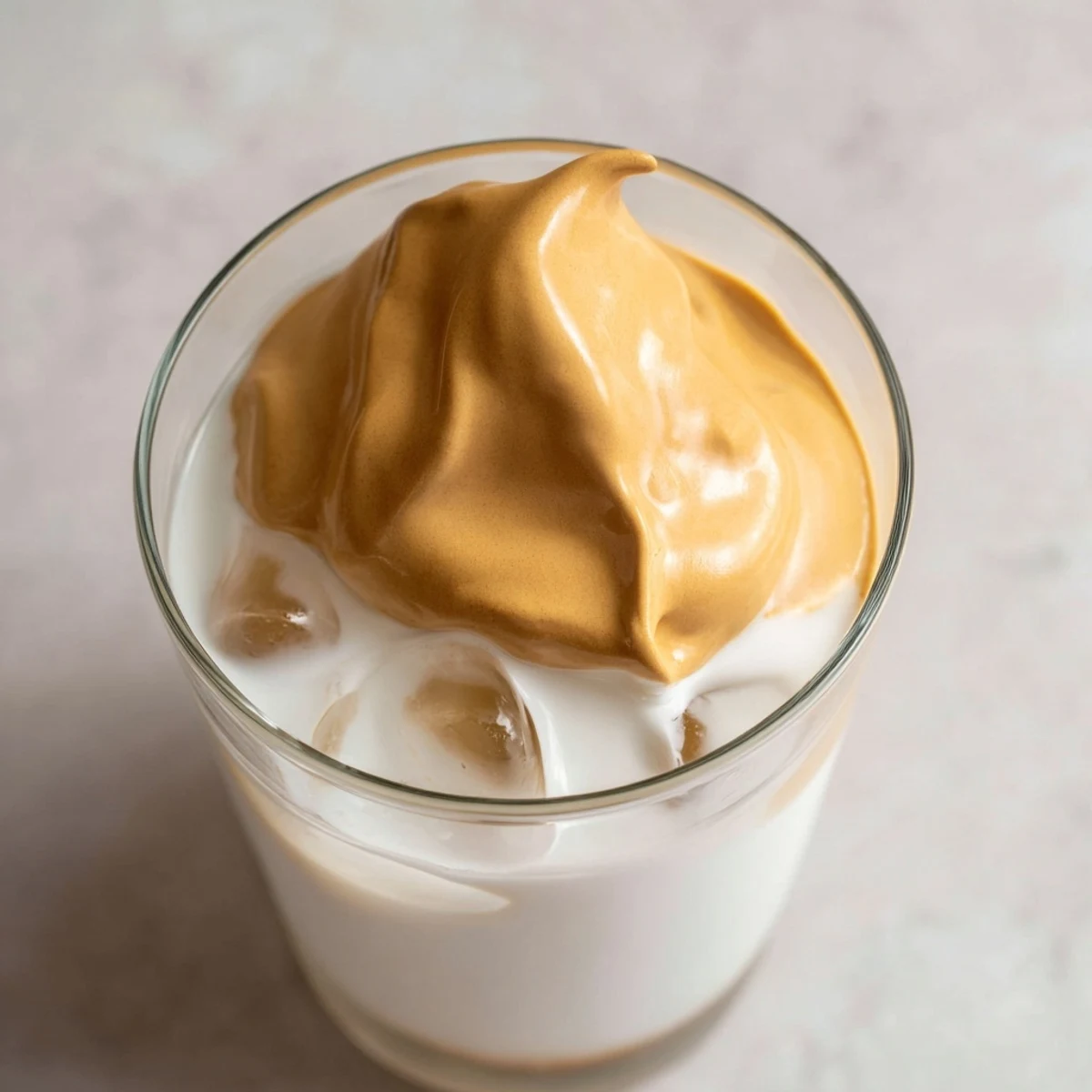 Homemade Dalgona coffee with velvety whipped instant coffee on chilled milk, perfect for a quick Korean-inspired beverage.