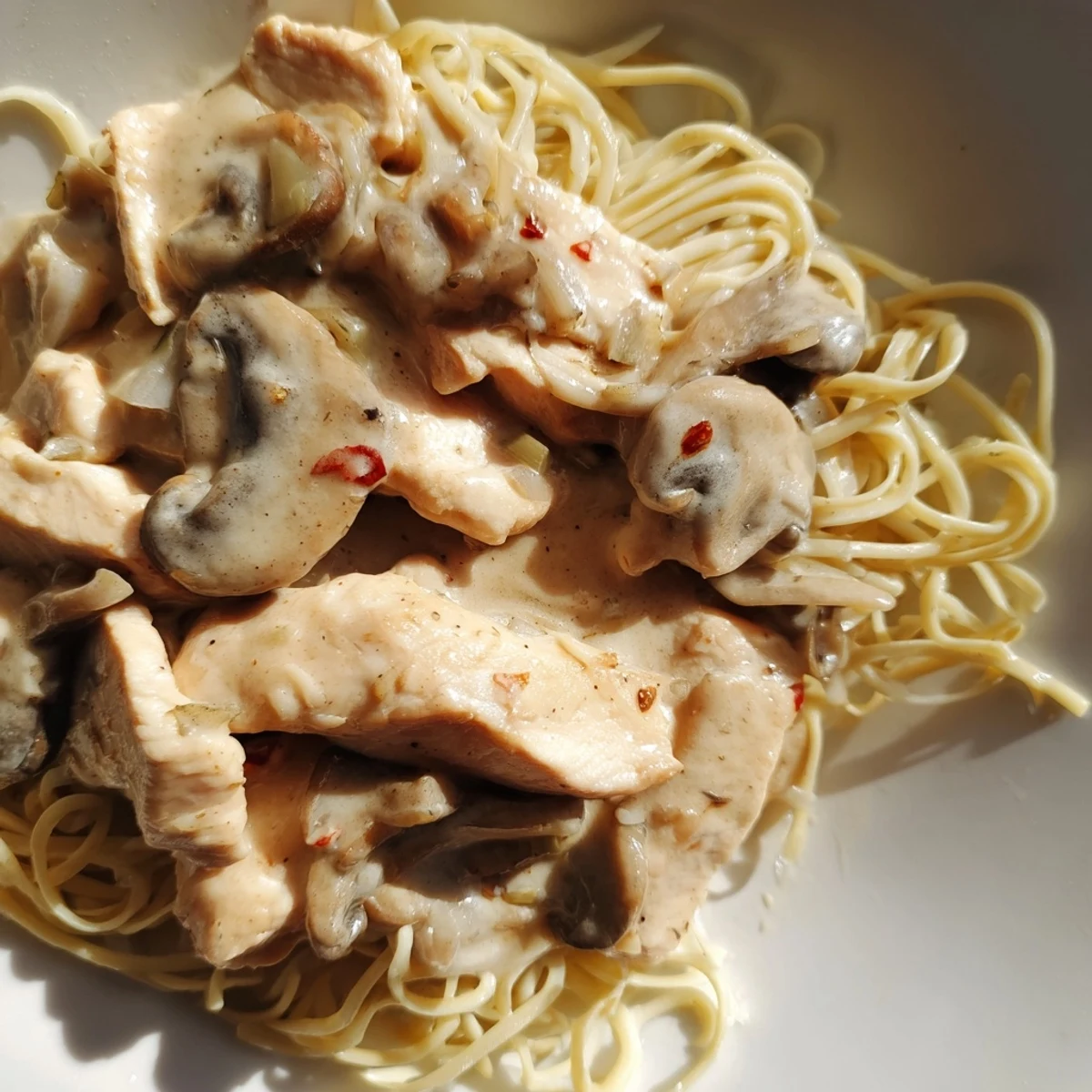 A close-up of Chicken and Mushroom Stroganoff showcases tender chicken and sautéed mushrooms in a rich, velvety sauce, garnished with fresh parsley.  