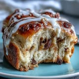 Fluffy, freshly baked hot cross buns, warm from the oven and glistening with apricot glaze, filled with juicy raisins and fragrant spices for Easter morning.  