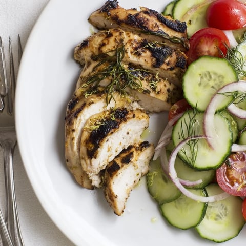 Grilled Lemon Herb Chicken perfectly garnished with vibrant cucumber salad and fresh herbs.  