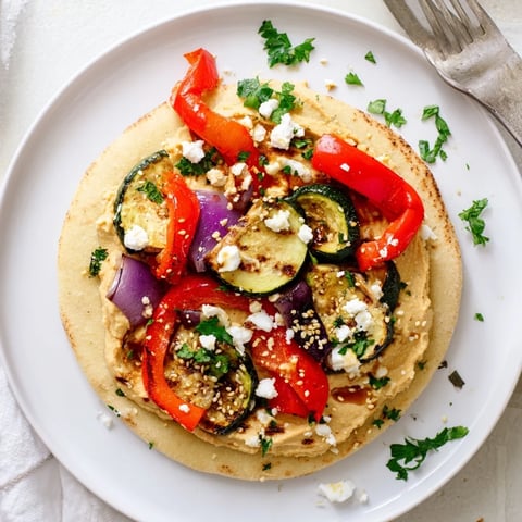 Soft flatbreads topped with creamy hummus, roasted veggies, and fresh herbs.