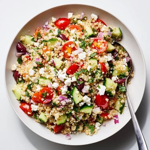 Vibrant Mediterranean Quinoa Salad with Feta topped with fresh herbs and colorful veggies.  