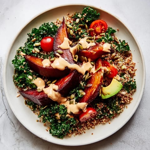 A colorful photo of a Quinoa, Kale & Roasted Beet Bowl with a creamy tahini dressing drizzled over it.