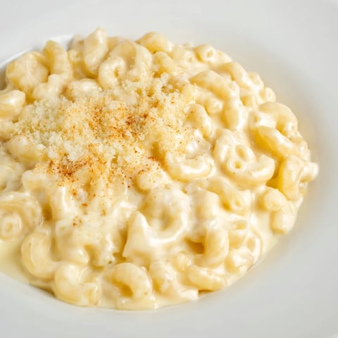 Steaming mug mac & cheese, topped with paprika and Parmesan, ready for a satisfying bite.