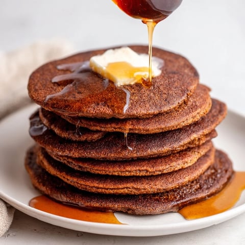 Golden gingerbread pancakes topped with melting butter and glistening syrup, ready to enjoy.