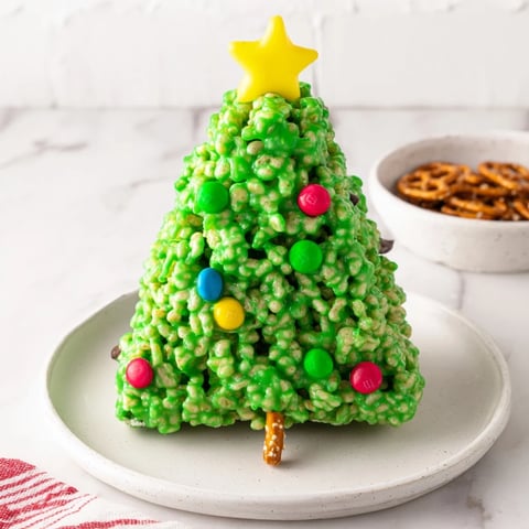 Festive green Christmas Tree Rice Crispy Treats topped with colorful candies and star decorations, perfect for the holidays.