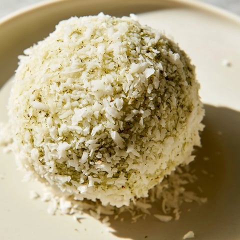 Creamy Coconut Matcha Snowball fat bombs covered in shredded coconut, ready to eat.