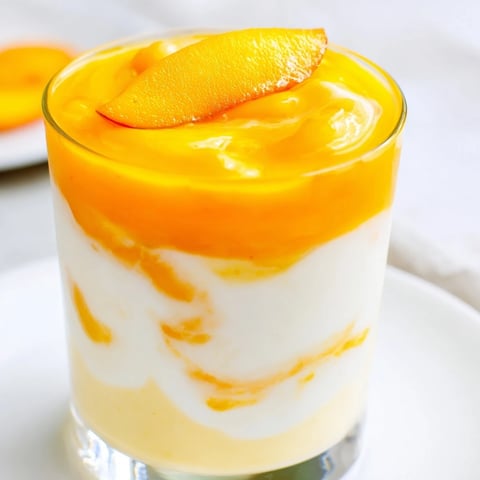 Vibrant, layered Tropical Sunset Smoothie, with creamy yogurt bands and fresh fruit garnishes, awaiting your first sip.