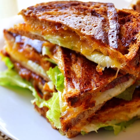 Golden-brown grilled Vegan Bacon BLT with melted vegan cheese, smoky tempeh bacon, fresh lettuce, and tomato slices on sourdough.