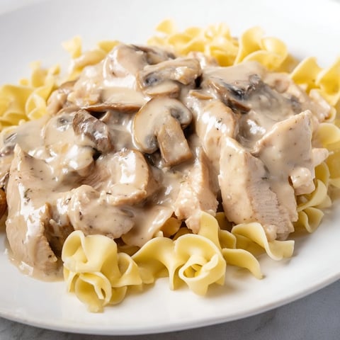Golden-brown chicken strips and earthy mushrooms simmer in a creamy paprika sauce, served over buttery egg noodles for a comforting Chicken and Mushroom Stroganoff.  