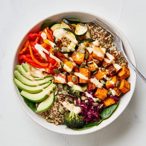 Vibrant roasted vegetables piled atop quinoa, drizzled with creamy tahini sauce.  