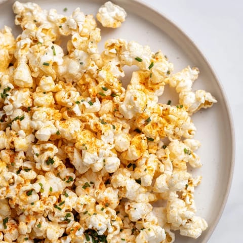 Golden, buttery savoury popcorn mixes tossed with fresh herbs, ideal for game day gatherings.