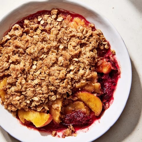 A close-up of a fruit crisp filled with sweet, frozen fruit just out of the oven.