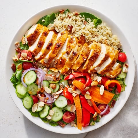 A colorful bowl of Crunchy Quinoa Chicken Salad, showcasing fresh vegetables and toasted seeds.
