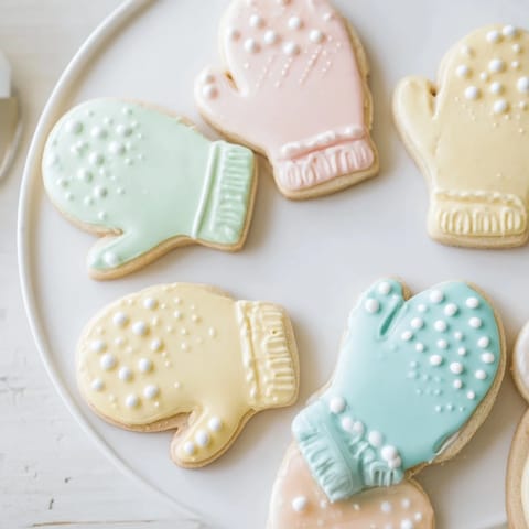 Warm and toasty mitten cookies, iced in colorful designs, ready to be enjoyed at a holiday gathering.