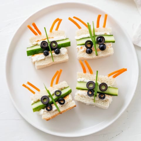 Vibrant arrangement of cute bee sandwich cutouts with fresh grapes and carrots, perfect for a picnic.