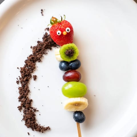 Fresh and fun Caterpillar Fruit Skewer Track with strawberries and grapes displayed on a crumb path.