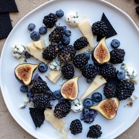 This Deep Indigo Midnight Sky cheese board features dark fruits, creamy cheese, and black rice crackers ready to serve.