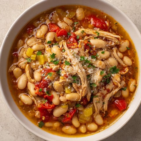 A steaming bowl of creamy white bean and roasted red pepper chicken, perfect for a cozy dinner.