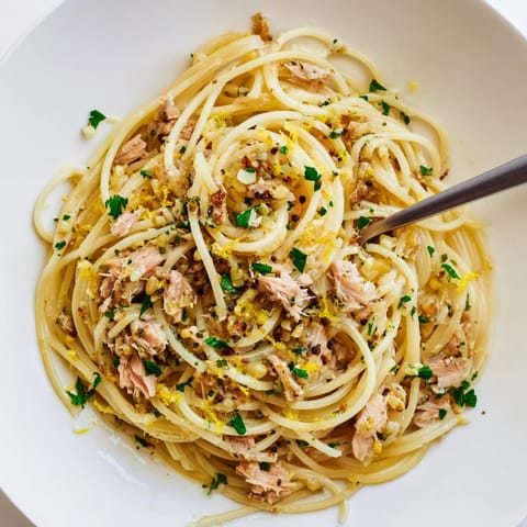 Bright, flavorful photo of Lemon-Garlic Tuna Spaghetti with parsley garnish and lemon wedges.