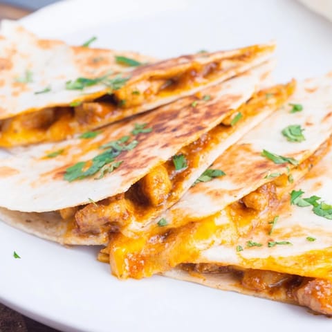 Melted cheese spills from crispy tortillas, showcasing flavorful Butter Chicken Quesadillas perfectly cut.