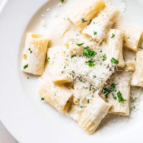 Fork twirling penne pasta coated in silky, milk-based sauce from the Creamy Milk Pasta One-Pot, garnished with Parmesan and black pepper.
