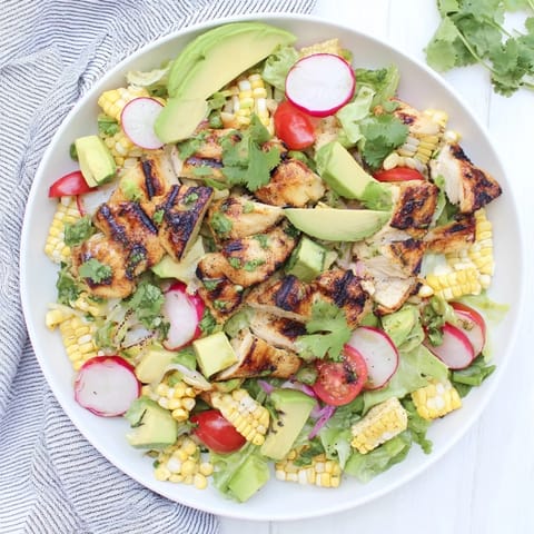 Bright lime dressing coats tender grilled chicken, sweet corn kernels, diced avocado, and colorful cherry tomatoes in this refreshing Roasted Corn & Chicken Chopped Salad.