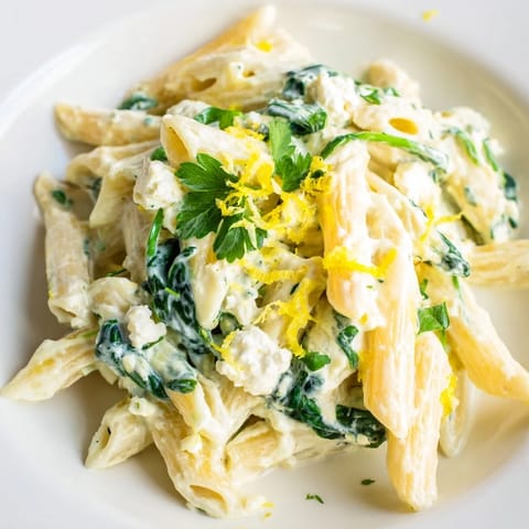 Velvety Creamy Feta Spinach Pasta twirled on a fork, showing melted feta sauce and wilted spinach leaves.  