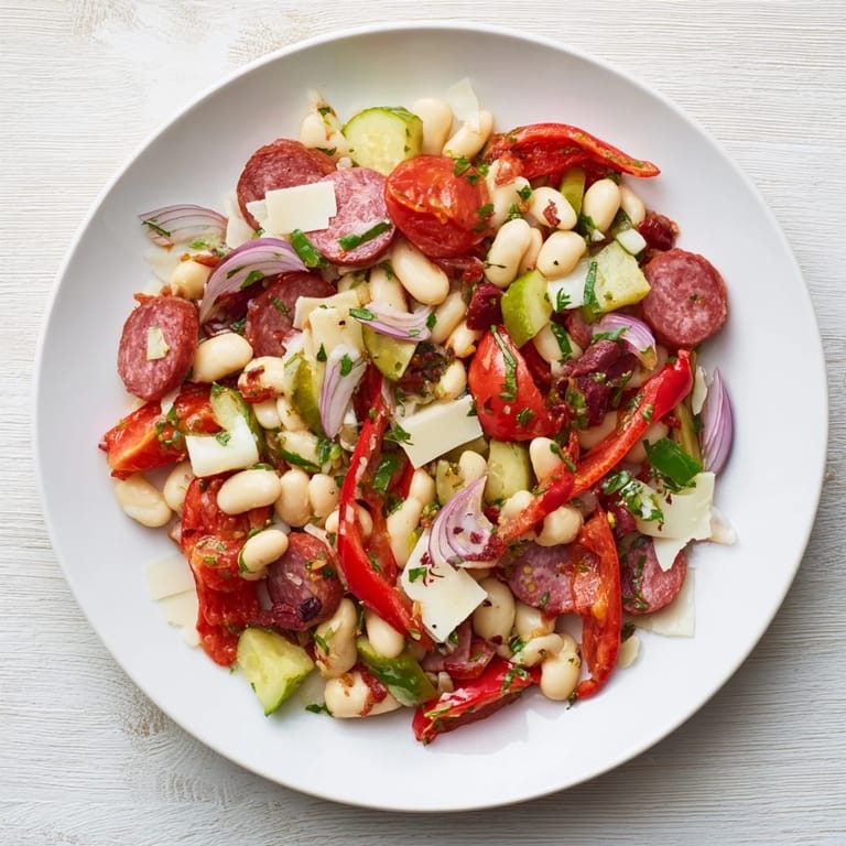 A delicious Italian Antipasto Bean Salad, showing a close-up of salami, provolone, and vibrant tomatoes.