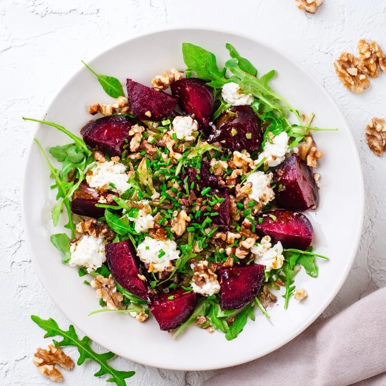 Roasted beet goat cheese salad over arugula, featuring ruby-red beet wedges, creamy crumbles, and crunchy walnuts in bright light.  
